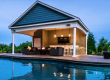 Luxury outdoor bar structure with covered seating and backyard entertainment space.