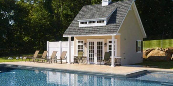 Prefab Pool House vs Custom-Built Modern prefab pool house beside a luxury backyard swimming pool with outdoor lounge furniture and landscaped garden.