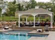 Custom backyard entertainment structure with outdoor seating and landscaped gathering area.