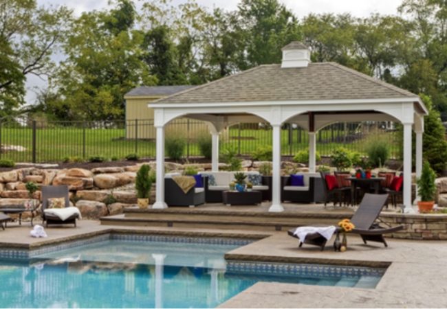 Custom backyard entertainment structure with outdoor seating and landscaped gathering area.