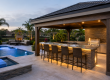 Luxury backyard pool area featuring a covered pool bar and outdoor seating